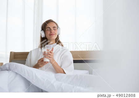 Woman holding glass of milk and listening relax 49012808