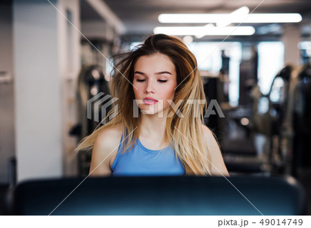 A portrait of young girl or woman doing cardio workout in a gym. 49014749