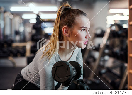 Young girl or woman with dumbbells, doing workout in a gym. 49014779