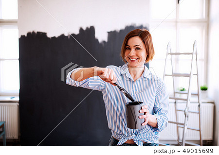 A portrait of young woman painting wall black. A startup of small business. A portrait of young woman painting wall black. A startup of small business. 49015699