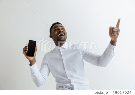 Indoor portrait of attractive young black african man isolated on pink background, holding blank 49017024
