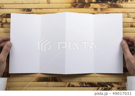 Mens hands holding white booklet 49017031