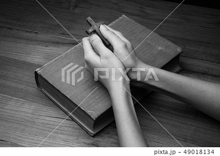 Hands folded in prayer over Holy Bible 49018134