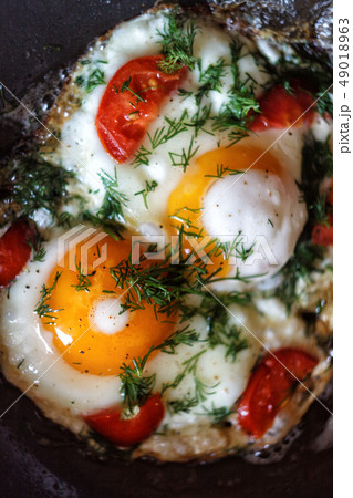Fried eggs with vegetables and herbs in a pan, on 49018963