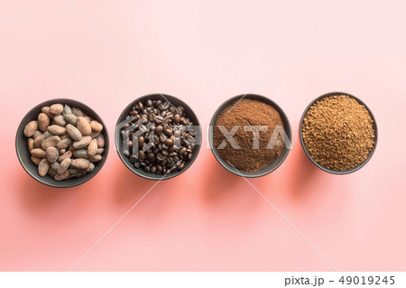 Concept of cocoa and coffee beans in bowls on pink Concept of cocoa and coffee beans in bowls on pink 49019245