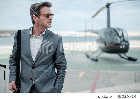 Businessman talking on cellphone near private helicopter Businessman talking on cellphone near private helicopter 49020714