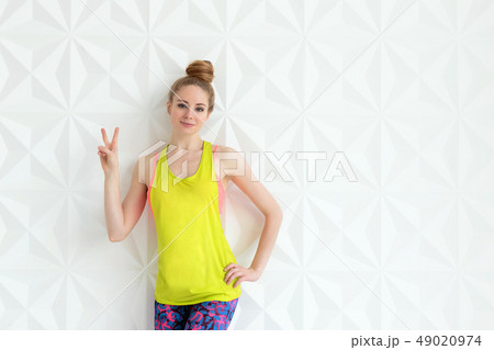 Sporty young woman posing over white wall background showing victory or peace sign Sporty young woman posing over white wall background showing victory or peace sign 49020974