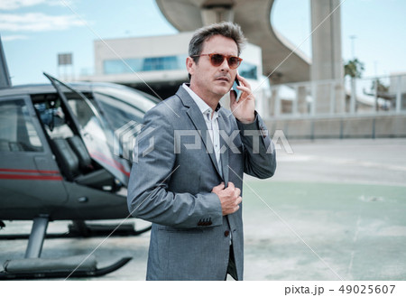 Businessman standing near private helicopter Businessman standing near private helicopter 49025607
