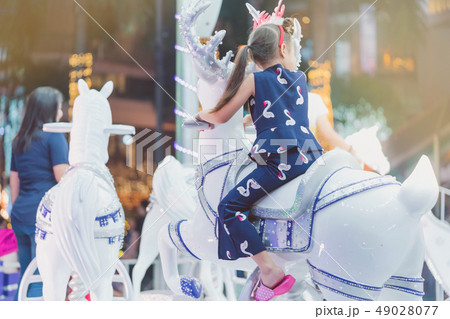 Adorable Asian little kid girl riding on a merry Adorable Asian little kid girl riding on a merry 49028077