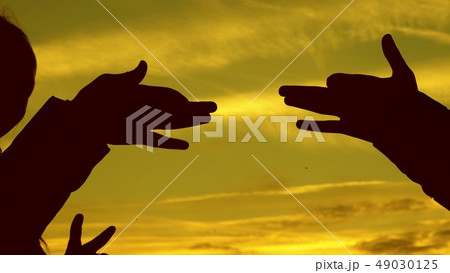 Children make shape of dog shape with hands at sunset. girls hold the gesture of a dog symbol with 49030125
