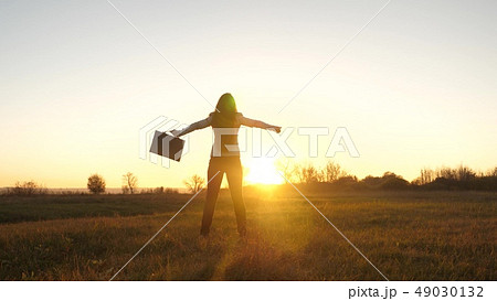 Free business woman with briefcase in her hand and in business suit is success at sunset in bright 49030132