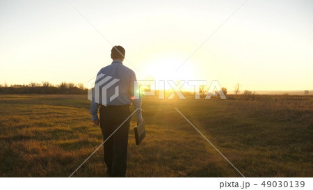 Business man with briefcase goes on beautiful sunset after working day 49030139