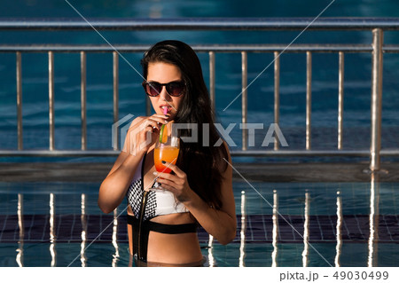 pretty woman drinking a cocktail in a pool pretty woman drinking a cocktail in a pool 49030499