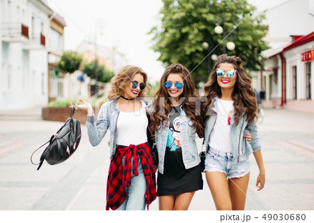 Tredny smiling girlfriends walking along the Tredny smiling girlfriends walking along the 49030680