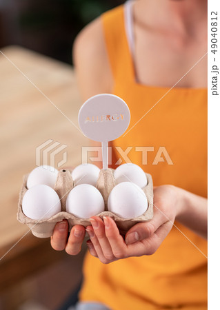 Young lady in bright yellow t-shirt holding bunch of eggs 49040812