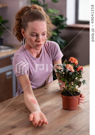 Unfortunate curly woman having allergic reaction on plant Unfortunate curly woman having allergic reaction on plant 49041358