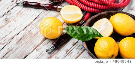 Smoking hookah with lemon flavor Smoking hookah with lemon flavor 49049543