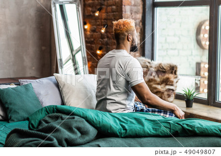 Nice pleasant man sitting on the bed Nice pleasant man sitting on the bed 49049807