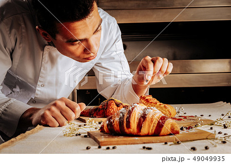 Talented professional baker finishing decoration of pastry desserts Talented professional baker finishing decoration of pastry desserts 49049935