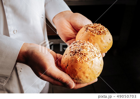 Baker wearing white jacket holding two little buns 49050703