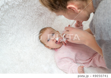 mother nasal aspiration sucks the snot from baby 49050741