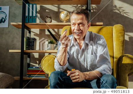 Smiling short-haired man in blue jeans holding a pill Smiling short-haired man in blue jeans holding a pill 49051813