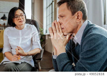Upset short-haired man in blue sweater looking aside while discussing Upset short-haired man in blue sweater looking aside while discussing 49052838