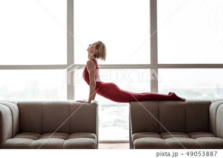 Appealing strong woman in bright red outfit performing yoga 49053887