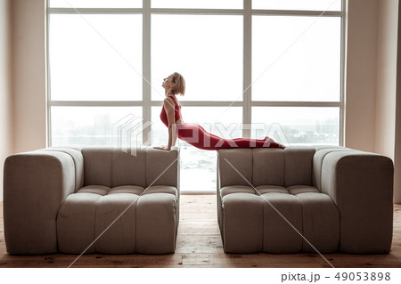 Flexible short-haired young woman stretching her body during yoga session 49053898