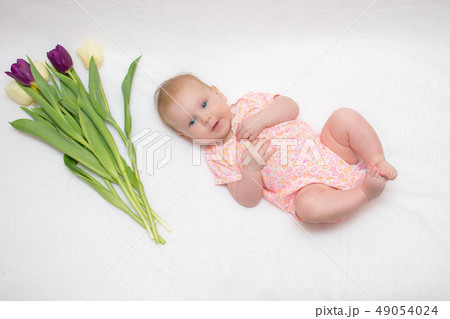 baby lies on a plaid next to a bouquet of tulips baby lies on a plaid next to a bouquet of tulips 49054024