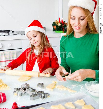 Adorable girl with her mother baking Christmas Adorable girl with her mother baking Christmas 49054495