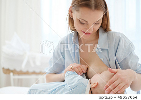 Happy middle aged mother breast feeding her baby 49057064