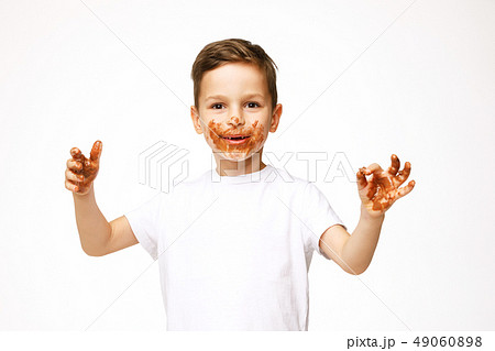 little boy with face and hands in chocolate little boy with face and hands in chocolate 49060898