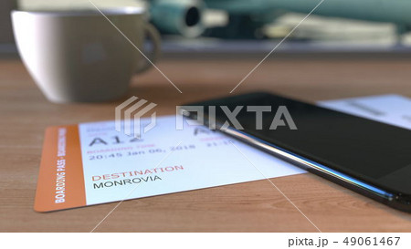 Boarding pass to Monrovia and smartphone on the table in airport while travelling to Liberia. 3D 49061467