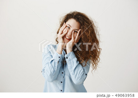 Young girl standing isolated on grey wall playing around looking camera smiling happy close-up 49063958