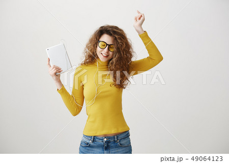 beautiful woman in headphones listening music and using digital tablet isolated on grey. beautiful woman in headphones listening music and using digital tablet isolated on grey. 49064123