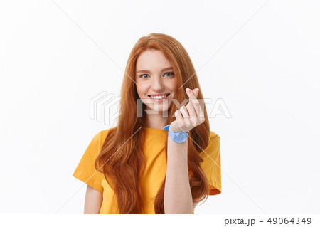 Pretty romantic young redhead woman making a heart gesture with a happy tender smile 49064349