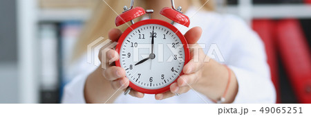 Smiling business woman holding in hand clock Smiling business woman holding in hand clock 49065251