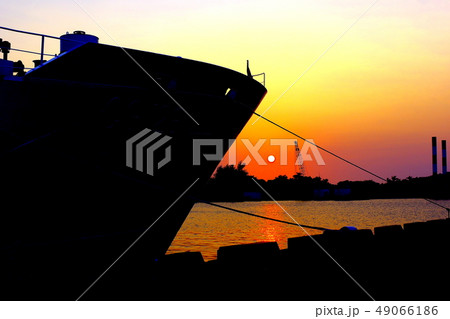 台湾 高雄市高雄港の夕暮れ 日没シーン 強烈な船首のシルエットと夕焼け風景 の写真素材