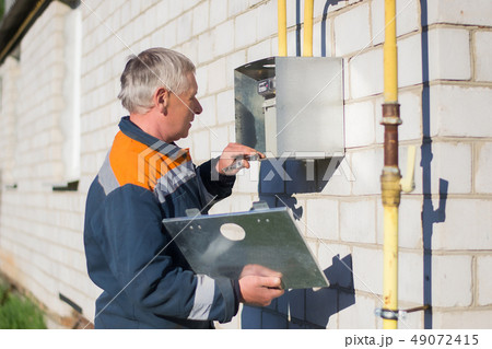 specialist man repairs a gas meter hanging 49072415