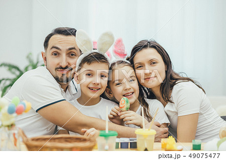 Happy family sitting at the table full og easter supplies, hugging and smiling. Children in funny 49075477