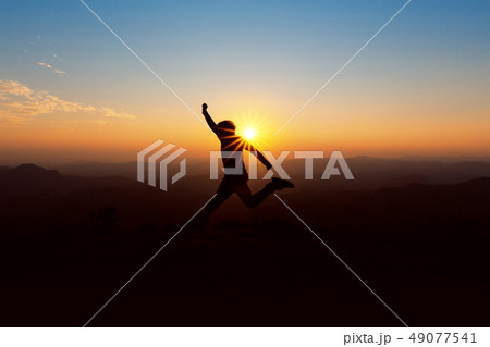 People jump on top of the mountain at sunset. 49077541