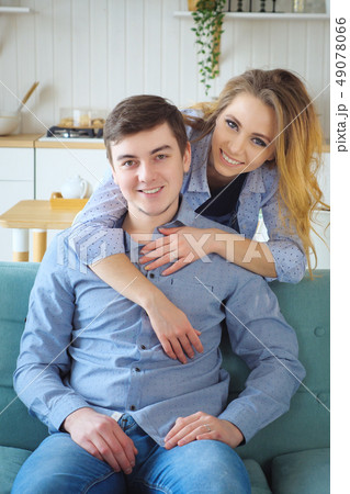 blond girl hugging a guy from behind in the kitchen blond girl hugging a guy from behind in the kitchen 49078066