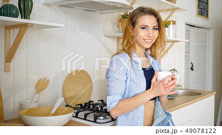Young girl drinks coffee and smiling at kitchen Young girl drinks coffee and smiling at kitchen 49078122