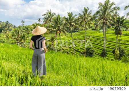 Relaxed fashionable caucasian female tourist wearing small backpack and traditional asian paddy hat Relaxed fashionable caucasian female tourist wearing small backpack and traditional asian paddy hat 49079509