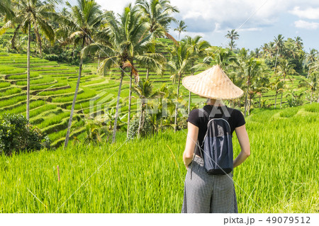 Relaxed fashionable caucasian female tourist wearing small backpack and traditional asian paddy hat Relaxed fashionable caucasian female tourist wearing small backpack and traditional asian paddy hat 49079512