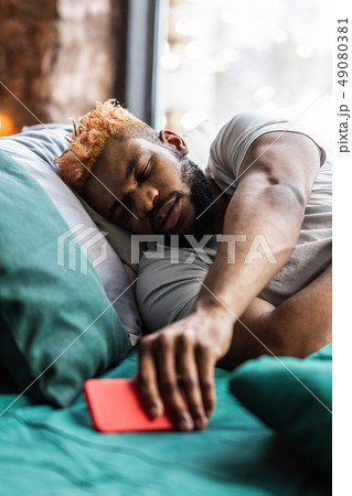 Good looking sleepy man hearing a message sound Good looking sleepy man hearing a message sound 49080381