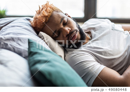 Pleasant bearded man lying on the bed Pleasant bearded man lying on the bed 49080448