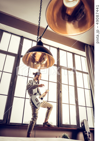Bearded musician wearing beige trousers feeling active playing rock 49087441