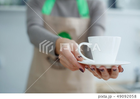 Barista in apron in coffee shop give just brewed Barista in apron in coffee shop give just brewed 49092058